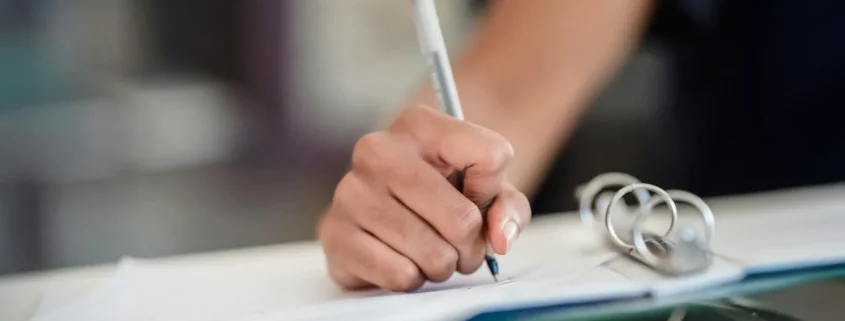 A hand writing on paperwork