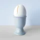 A photo of a cracked egg in an egg holder